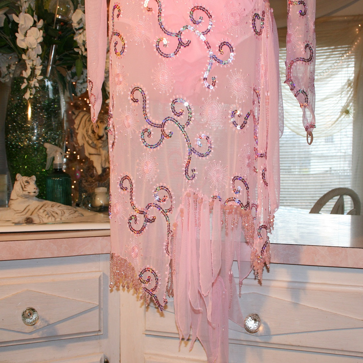 bead details of  stunning pink Latin-Rhythm dress. Its delicate soft pink stretch mesh is adorned with a mesmerizing scroll design, highlighted by two shades of glimmering pink rhinestones in a beautiful scroll design on the back, upper bodice, and left sheer side. The extensive hand beading in the skirting adds the perfect touch of elegance